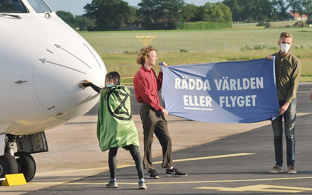 Photograph of action with rebels holding banner "Save the world OR aviation."