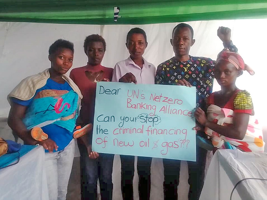 Author David Jesero stands with four women holding a sign that says: Dear UN's Net-Zero Banking Alliance, can you stop the criminal financing of new oil & gas?? 