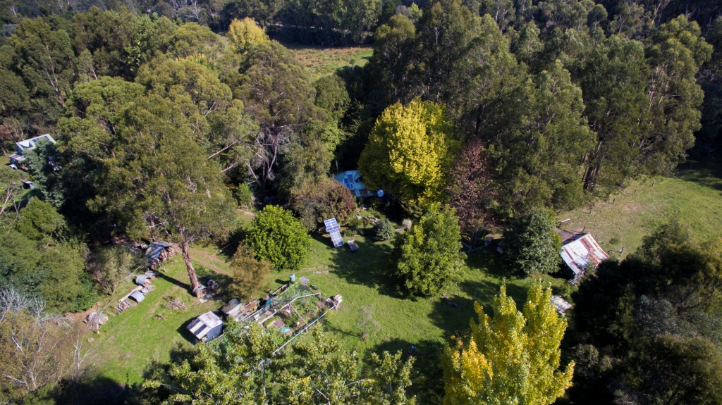 Aerial view of Witchwood farm in Goongerah, East Gippsland, Australia, including trees, sheds and a solar panel 